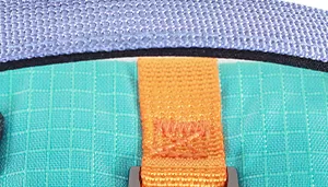A rectangular swatch showing multiple materials and colors associated with the Atlantic colorway. The upper portion features a woven light blue fabric with a visible textured weave. Below it, a section of teal woven material is displayed, showing a grid‑like texture. Centered over the teal area is a vertical orange woven strap with a coarse, durable texture. A thin dark‑navy trim line separates the upper and lower fabrics. The swatch highlights the layered, multi‑fabric construction used in the Atlantic colorway.