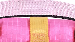 A swatch featuring a section of soft rose‑pink fabric with fine black seams. A strip of smooth golden‑yellow webbing is attached vertically across the pink surface. The textures include the matte pink material, sturdy woven yellow band, and contrasting black stitching.